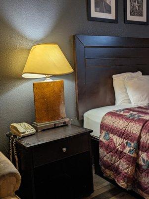 Warped lampshade by bed with scratched-up lamp decor