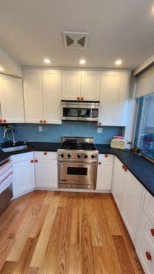 Custom kitchen cabinetry, tiling, and lighting. Handmade orange handles.