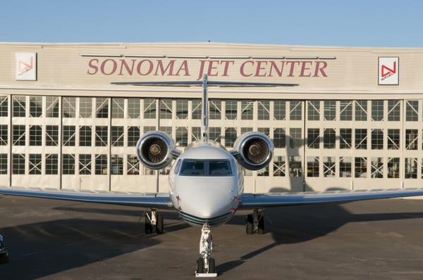 Cool airplane in front of a cool hangar.