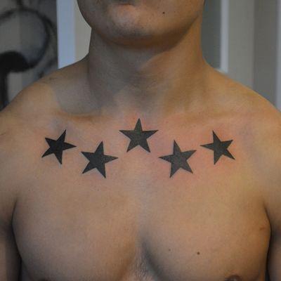 Five black star tattoos on the chest and clavicle