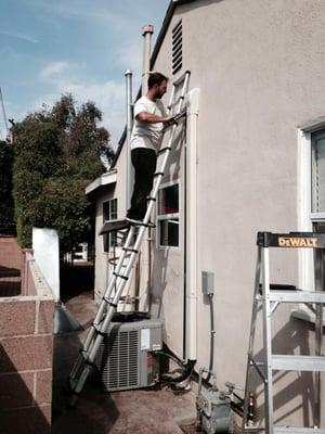 Our installer finishing sealing the external molded refrigerant line cover for this AC system we installed in an older home t...