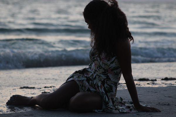 A teen girl laying on the sand at the beach