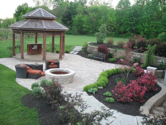 Outdoor living with a gazebo, firepit and patio with raised beds and retaining walls.