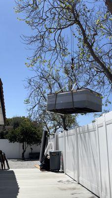 The spa being lifted over our fence