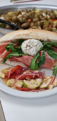 prosciuto burata panino with arugula and cucumber tomato salad on the side