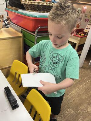 Practicing fine motor skills in writing center, hole punches are a hit!