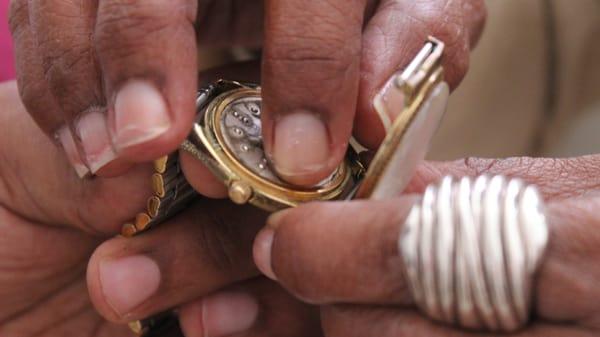 A close up of a person touching a Braille watch, telling time tactilely.