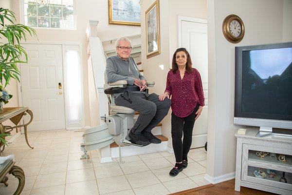 man on stair lift next to his wife in their home in Delaware