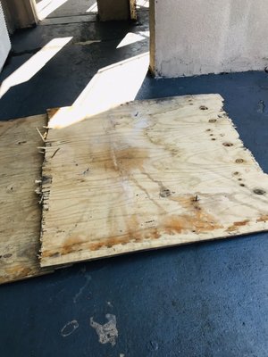 A board laying outside a door away with nails sticking up