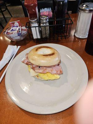 Breakfast sandwich on bagel with ham cheese and egg.