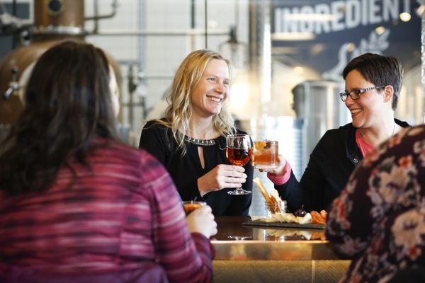 Picture windows of copper pot still graces as a backdrop to these friends catching up.