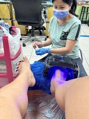 Technician doing shellac pedicure