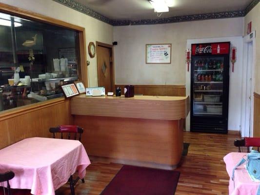 Takeout waiting area. Kitchen on left, restrooms on right. Two two-person tables.  Very neat and very clean.