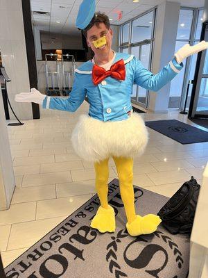 Mitch in an embarrassing Donald Duck costume checking into Sheraton hotel lost bet