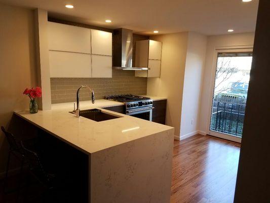 Glass front upper cabinets. Water fall Sile Stone quartz top.