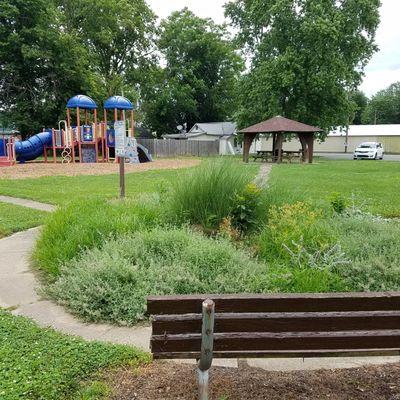 plantings and playground with a small shelter