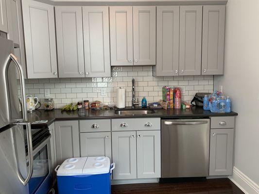 Kitchen counter space with fridge, dishwasher, and cooktop in Cecilia Suite