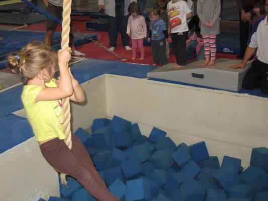 Kids get to try out the swing rope and drop down into the foam squares.