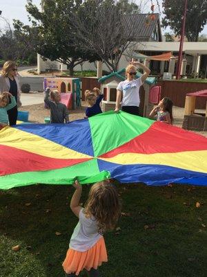 Mrs. Brittney having a fun time with some wonderful kiddos, while using a parachute (along w/music) to show them cool team building skills!!