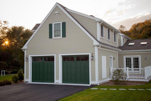 Green steeel carriage house garage doors with composite overlays and 3 pane square windows