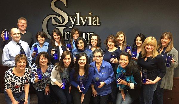 Members of the Sylvia Group staff, dressed in blue in recognition of World Water Day, raise a toast to the Buzzards Bay Coalition.