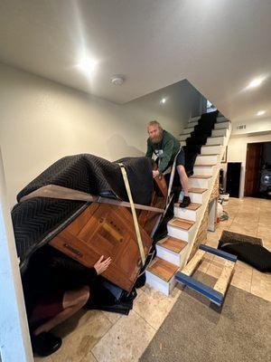 Baby grand piano being moved upstairs