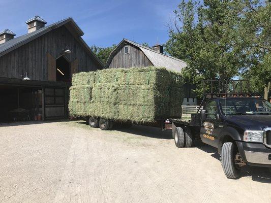 Unloading a lot of hay at a customer's location.