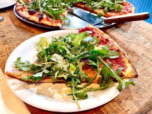 Perfect slice of thin Sicilia pizza with imported Speck and vibrantly great arugula!