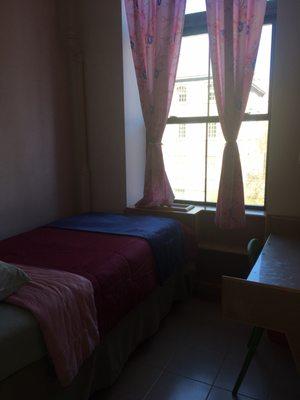 Bedroom with window, desk on the side with shelves.