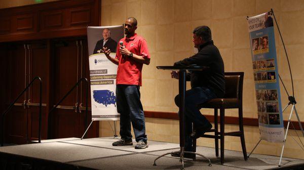 A member speaks at a nationwide touring event called Lifestyles Unlimited On Location. National Multifamily Mentor, JB Durham, sits right.