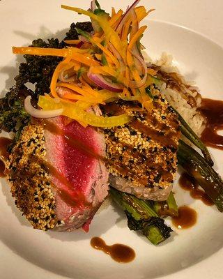 Sesame Crusted Ahi Tuna Topped with Hoisin Glaze and Pickled Vegetables. Served with Ginger Rice and Roasted Garlic Broccolini.