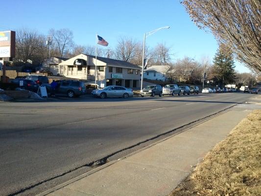 Cars lined up down the street to go through the wash on a sunny day. Don't forget about us when it's cloudy!