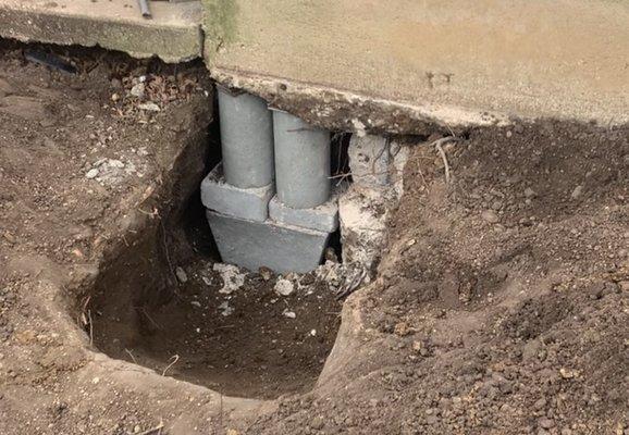 Concrete cylinders placed under concrete foundation to lift concrete for house leveling