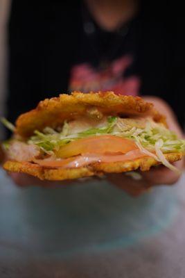 A grilled chicken patacon with lettuce and tomato