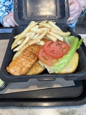 Salmon sandwich with side of fries.