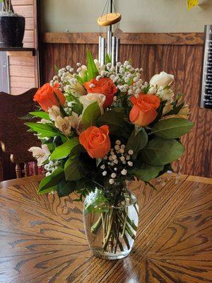 pastel pink alstro, pastel orange roses, white spray roses, pittosporum in low cylinder vase