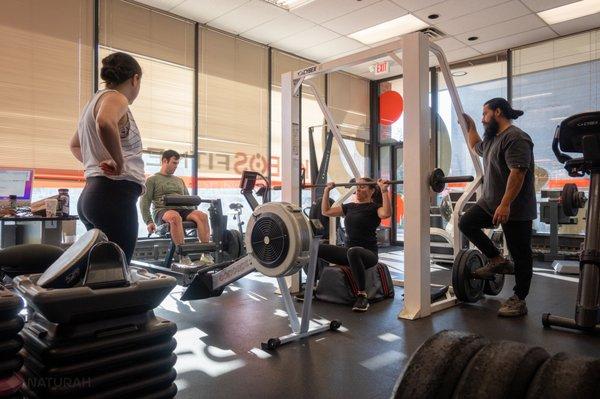 Trainer Alex guides his clients towards their fitness goals, while overseeing their progress and making adjustments to their routine.