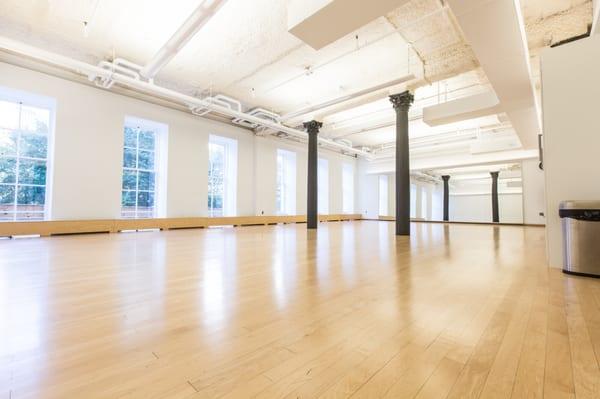 Studio D: A large, well-lit space with huge windows and two pillars, perfect for yoga class.