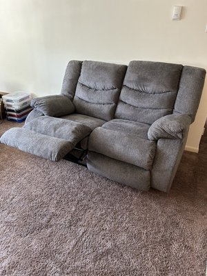 A grey reclining loveseat with one side reclined