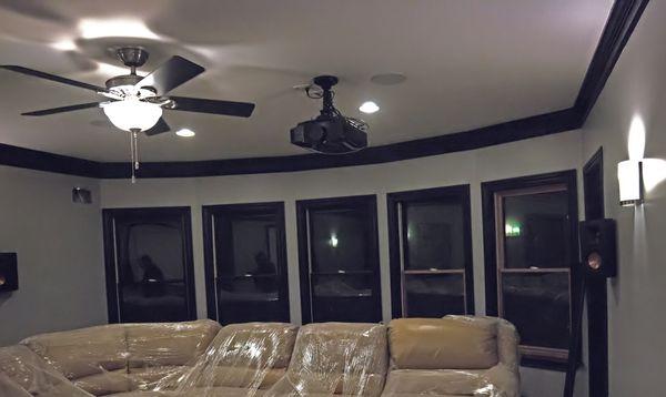 The projector tucked neatly away overhead with the Klipsch speakers focused on the seating area.