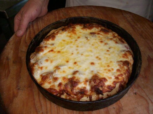 Pan pizza fresh from the oven, still in the pan.