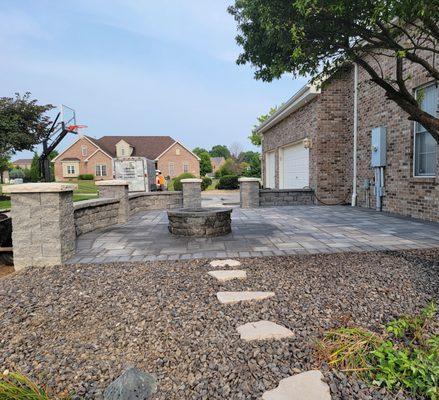 Paver patio with seating wall with pillars and fire pit.