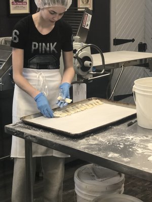 Girl making Kiffles from scratch and placing them on sheet.