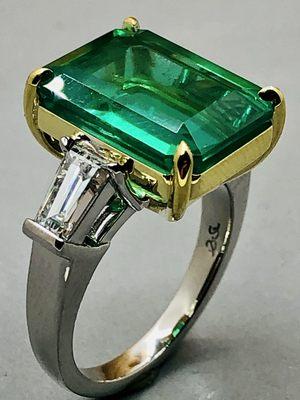 Emerald cut Zambian emerald ring with taper baguette side stones set in platinum and 18k yellow gold.