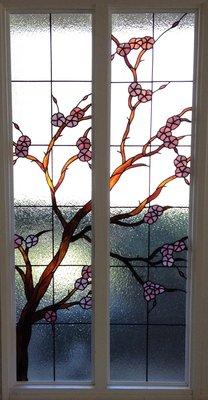 A cherry tree in stained glass provide privacy in the living room of a single lady.