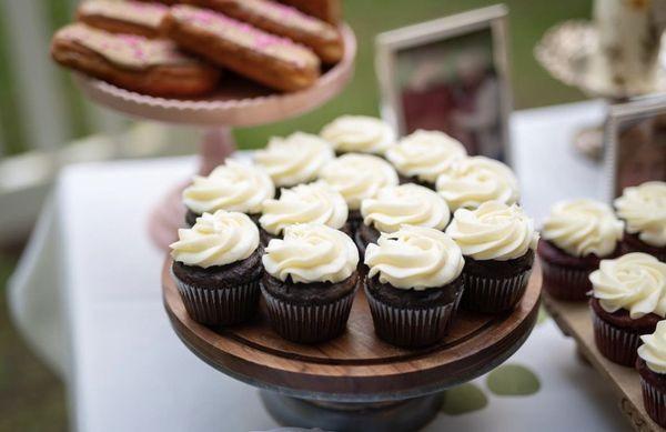 Chocolate cupcakes with vanilla buttercream and (to the right) red velvet cupcakes with cream cheese buttercream.