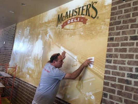 Installing the mural at McAllister's deli