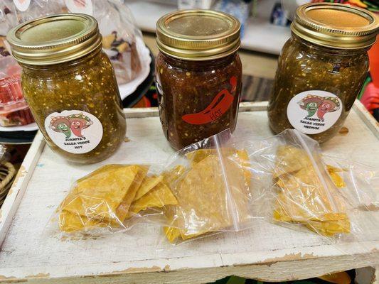 Homemade chips and homemade jars of red and green salsa