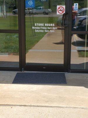 Front door with store hours posted.