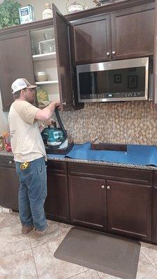 Ray Cleaning Up after Drilling into Cabinet